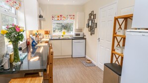 Una cocina moderna con una isla central, armarios blancos, microondas y lavavajillas.