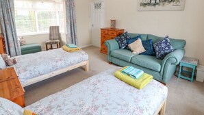 Una habitación acogedora con dos camas individuales, un sofá color turquesa y un pequeño aparador de madera.