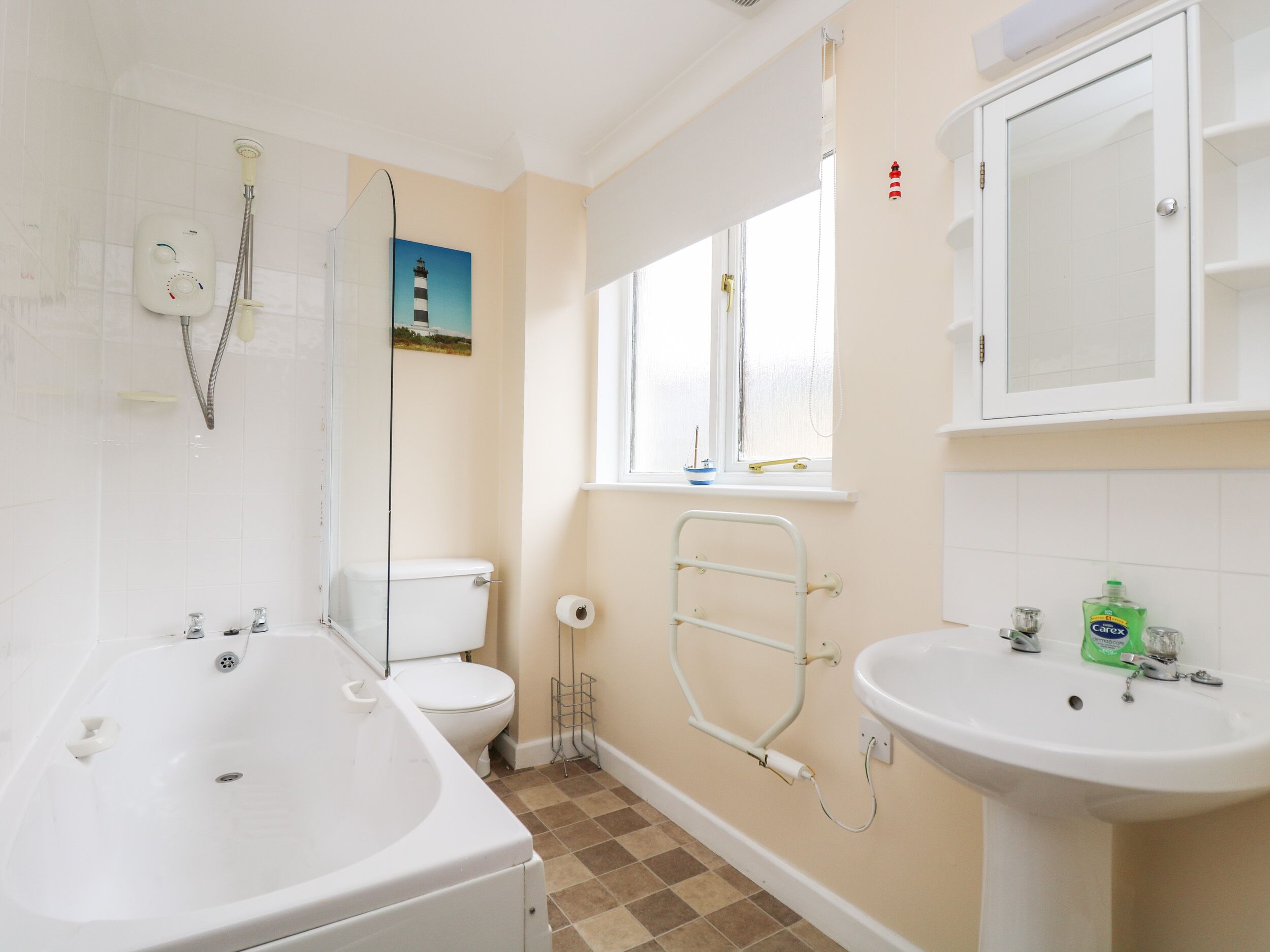 A bathroom with a bathtub, toilet, sink, and a window with a view.