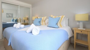 Camera d'albergo con un letto grande, due comodini, uno specchio e una lampada a parete.