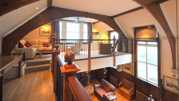Un loft spacieux avec de hauts plafonds, des poutres apparentes et de grandes fenêtres.