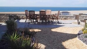 Une terrasse avec une table et des chaises donnant sur une plage.