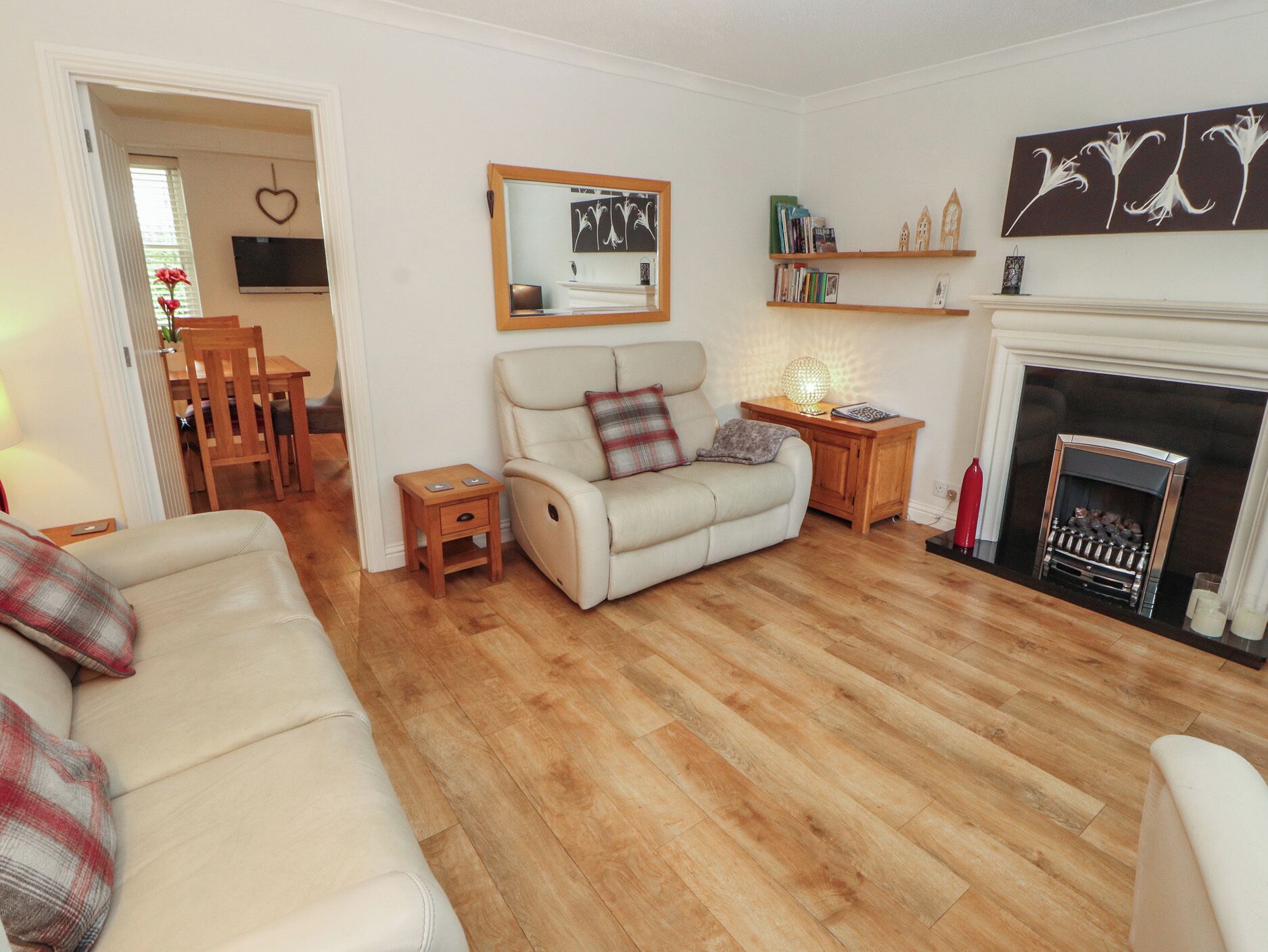 A living room with a sofa, a chair, a small table, a fireplace, and a bookshelf.