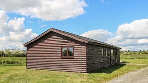 A wooden cabin with a gabled roof, a single window, and a door. - Rose Lodge (York)
