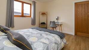 A bedroom with a bed, a desk, a chair, a wardrobe, and a window with curtains. - Rose Lodge (York)