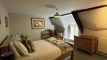 A bedroom with a bed, a chair, a dresser, a picture on the wall, and a window.
