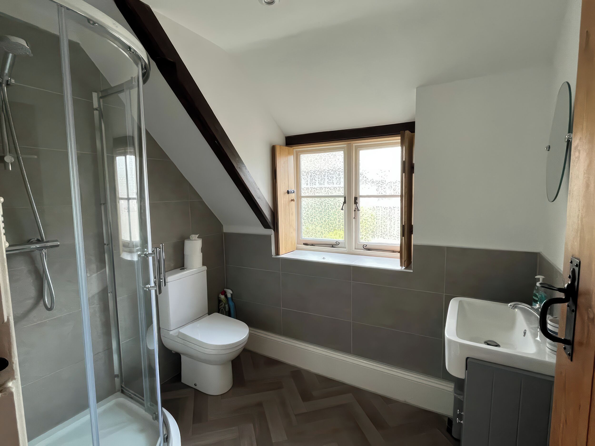 A bathroom with a shower, toilet, sink, and a window.