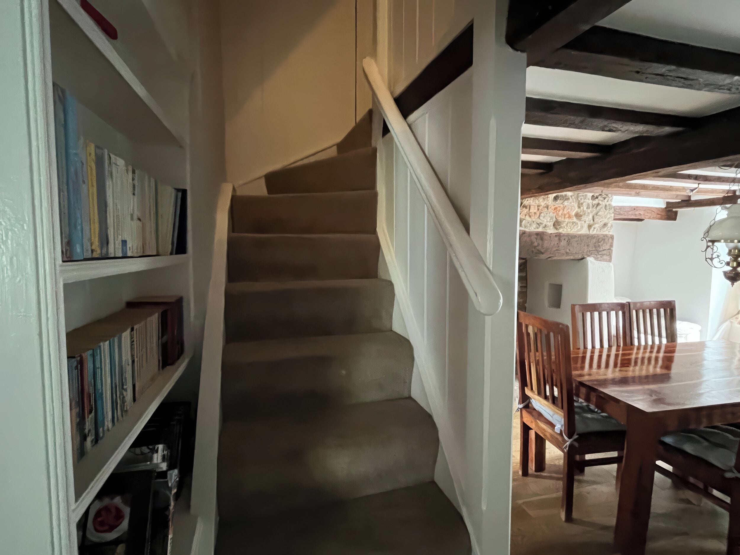 A staircase leading to a dining area with wooden chairs and a table.
