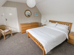 Un dormitorio con cama de madera, una silla de mimbre, cómoda de madera, mesita de noche con lámpara, espejo y una puerta con el rótulo "PRIVATE".