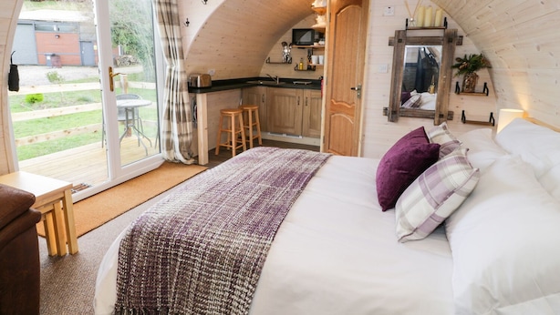A cozy bedroom with a large bed, a wooden ceiling, and a sliding glass door leading to a balcony. - Gelert Pod (Saint Asaph)