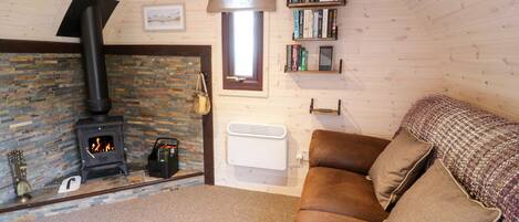 A cozy cabin interior with a stone fireplace, a bookshelf, and a comfortable couch.