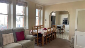 Un salon chaleureux avec un canapé, une table à manger et des chaises, et un coin cuisine visible à travers une arche.