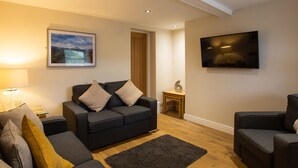 A modern living room with a sofa set, a coffee table, and a TV mounted on the wall. - Minafon (Llangollen)
