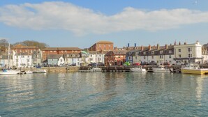 A harbor with boats docked, buildings along the waterfront, and a clear sky. - Reaver (Weymouth)