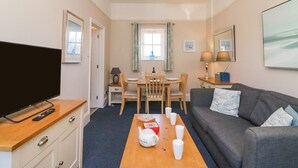A cozy living room with a flat-screen TV, a wooden coffee table, and a grey sofa. - Reaver (Weymouth)