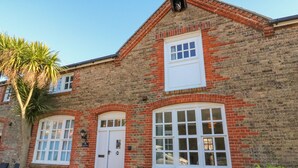 A brick building with a white door, large windows, and a small porch area with chairs. - Reaver (Weymouth)