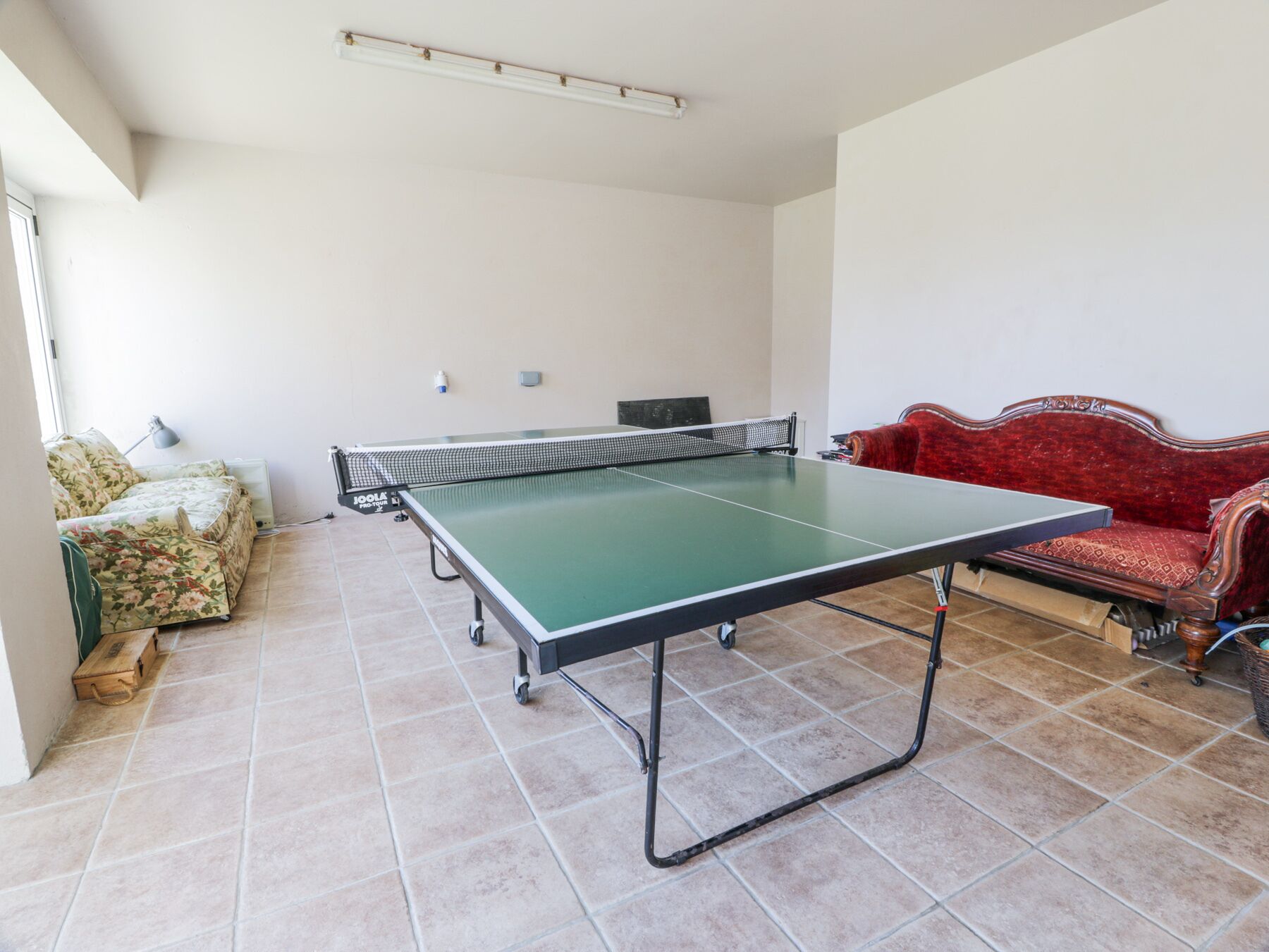 Una habitación con mesa de ping pong, un sofá y un sillón rojo.