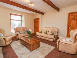 Una sala de estar con una mesa de centro de madera, sofás de cuero color beige y un florero con flores.