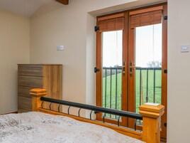 Un dormitorio con cama, armario de madera y un amplio ventanal con vistas a un paisaje verde.