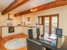 Una cocina moderna con vigas de madera, un comedor con mesa de vidrio y vistas amplias por ventanas grandes.
