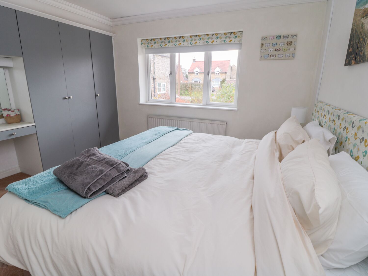 Une chambre à coucher avec un lit, une fenêtre donnant sur un beau paysage, une armoire et un radiateur.