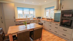 A modern kitchen with a wooden dining table, chairs, and a built-in oven. - Runswick (York)