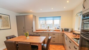 A modern kitchen with wooden flooring, a dining table with chairs, and built-in appliances. - Runswick (York)