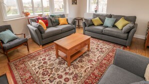 A living room with two grey sofas, a wooden coffee table, and a patterned rug. - Runswick (York)
