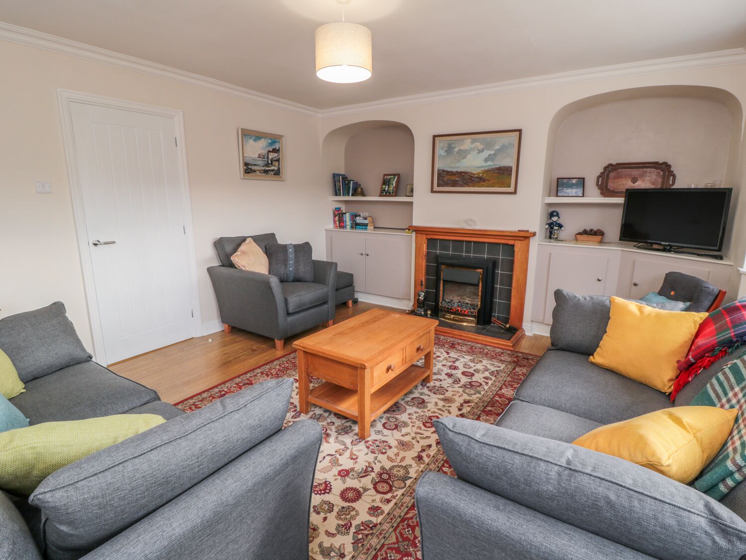 A living room with grey sofas, a wooden coffee table, a fireplace, and a television.