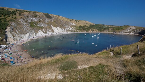 A coastal beach with boats, a sandy shore, and grassy hills. - Little Forge (Wareham)