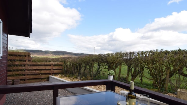 Un balcon avec une table, deux verres à vin et une bouteille de vin.