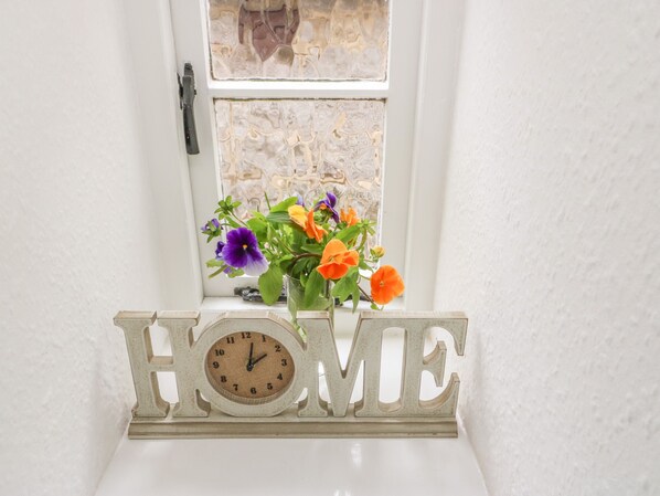 A white wall with a window, a clock, and a word "HOME" on a shelf. - High View Cottage (Hope Valley)