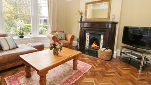 Ein Wohnzimmer mit Kamin, Ledersofa, Couchtisch aus Holz und einem Fernseher.