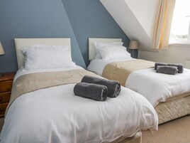 Habitación de hotel con dos camas, ropa de cama color crema y toallas grises.