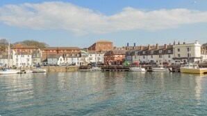 A harbor with boats docked, buildings along the waterfront, and a clear sky. - Maisy Cottage (Weymouth)
