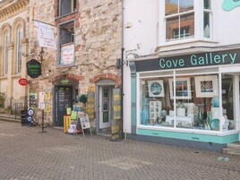 Una fachada con un cartel de Cove Gallery, una oficina de correos y un cartel de Londis Harbour Stores.