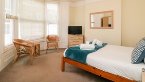 A bedroom with a bed, a television, a chair, and a dresser. - Louisa Cottage (Weymouth)