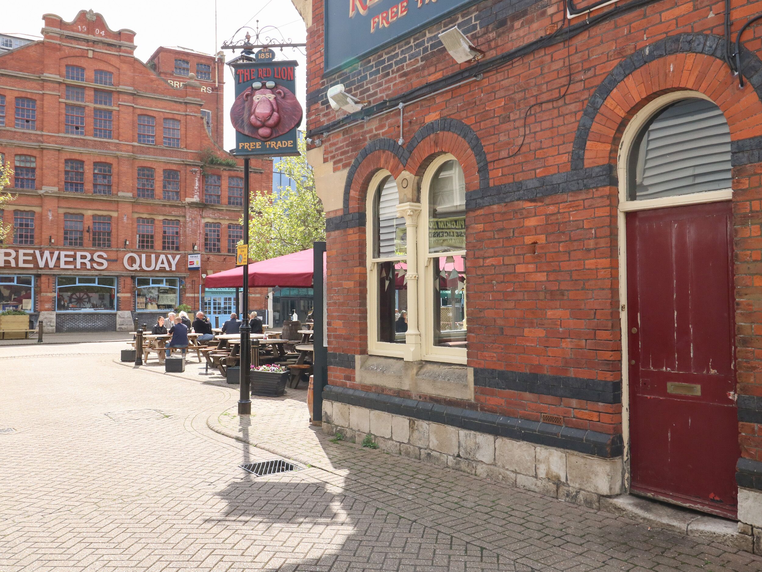 Un bâtiment en briques avec une porte rouge et une enseigne indiquant « The Red Lion Free Trade ».
