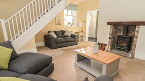 A living room with a staircase, a fireplace, and a sofa. - Hare &amp; Hounds House (Hexham)