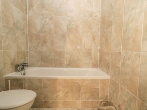 A bathroom with a bathtub, toilet, and tiled walls. - Hare &amp; Hounds House (Hexham)