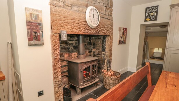 A cozy room with a stone fireplace, a wooden bench, and a clock on the wall. - Hare &amp; Hounds House (Hexham)