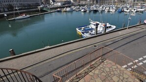 A marina with boats docked, a clear sky, and buildings in the background.