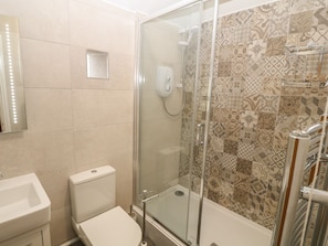 A bathroom with a glass-enclosed shower, a toilet, and a sink. - Fir Tree Cottage (Criccieth)