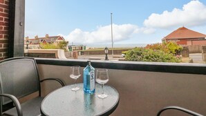 Un balcon avec une table, deux verres et une bouteille de spiritueux.