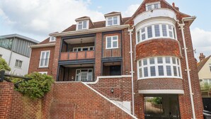 Une maison à deux étages, construite en briques, dotée d’un balcon, d’un garage et d’une allée d’accès fermée par un portail.