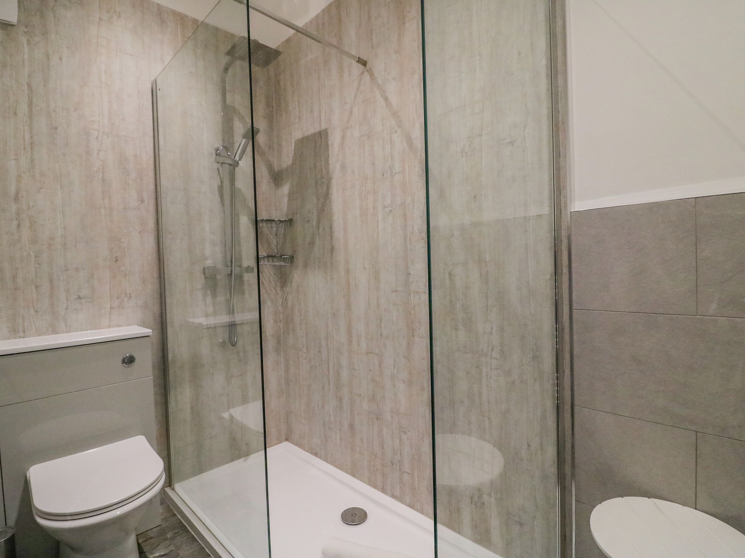Casa de banho moderna com cabine de hidromassagem em vidro, sanita e banheira.