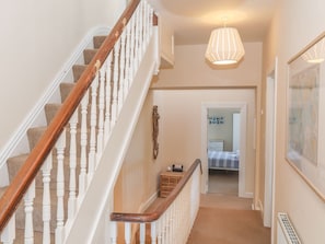 Classic design meets modern touches in this inviting space, featuring a staircase, pendant light, and cozy carpeted areas.