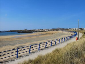 Enjoy the serene beach views and stroll along the metal railing.
