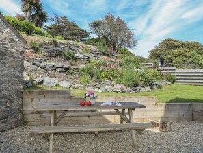 Relax in a serene garden setting with a rustic picnic table and bench.