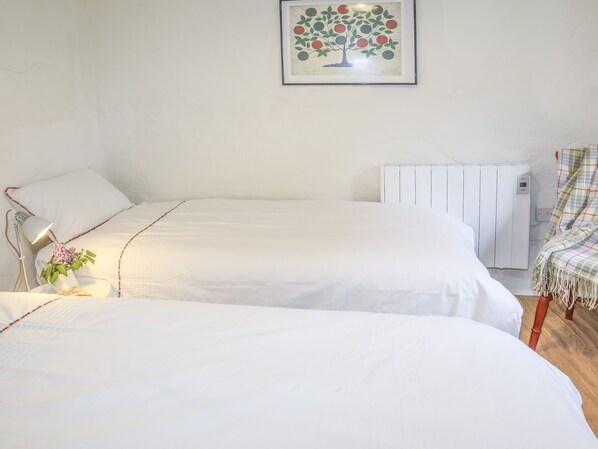 Une chambre avec deux lits, un radiateur, une lampe et un tableau encadré au mur.